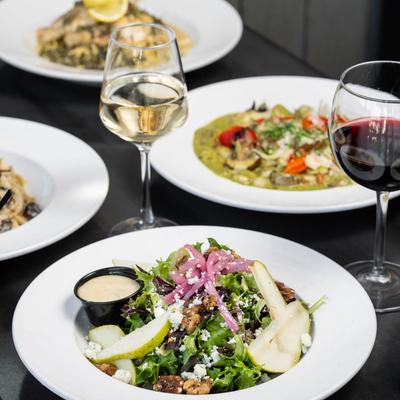 Multiple food plates and wine.