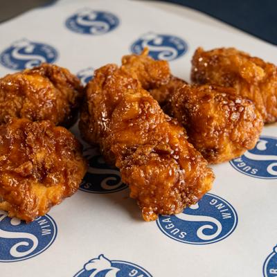 Fried boneless chicken wings served on branded parchment paper.