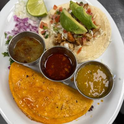 Open-faced chicken taco with avocado and birria taco served with salsas and lime.