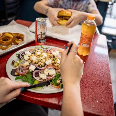 Two people having a meal at a restaurant table with drinks and a side of fries to share.