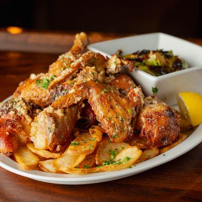 Roasted Garlic Parmesan Chicken served over fries, with a side of Brussels sprouts.