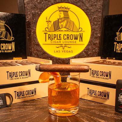 A cigar on a glass of whiskey placed in front of cigar boxes.