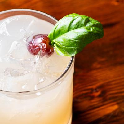 Passport cocktail with a grape and mint garnish.