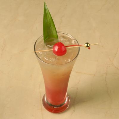 Caribbean Sunrise cocktail garnished with cherry and pineapple leaf.