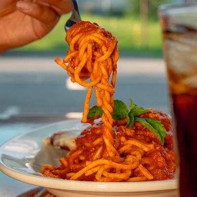 Spaghetti with rich red sauce lifted by a fork from a plate.