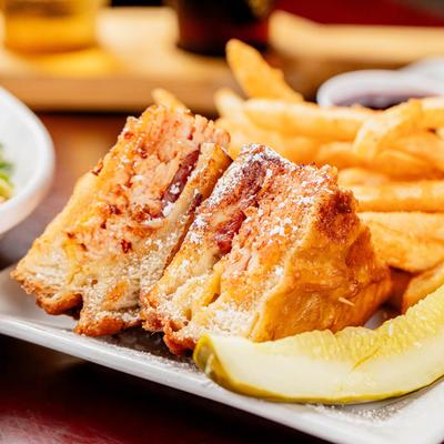 Monte Cristo sandwich with fries and a pickle spear.