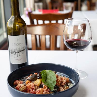 Rigatoni pasta with tomato sauce, eggplant and basil, served with red wine.