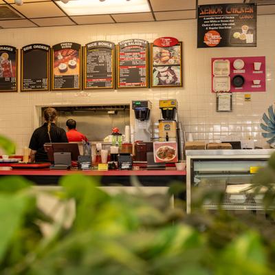Restaurant open kitchen viewed through green leaves.