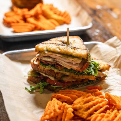 Grilled Chicken Club Sandwich served on a tray with waffle fries.