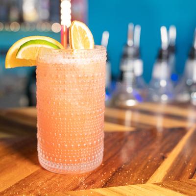 Paloma cocktail in a textured glass with citrus garnish.