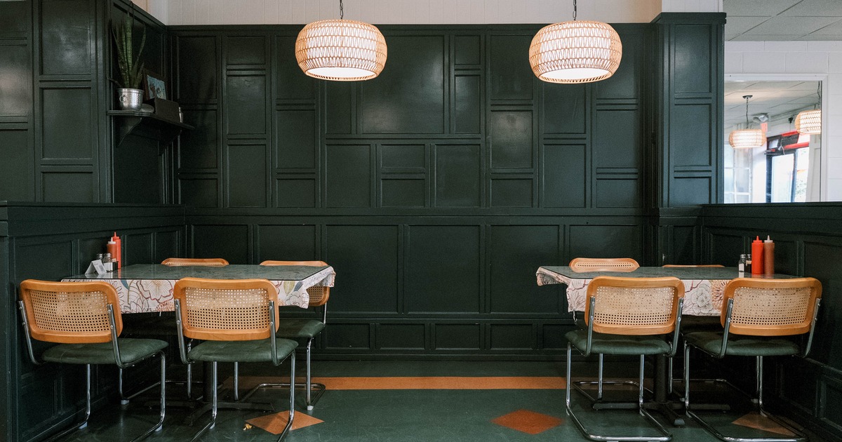 Interior - dark green paneled walls, tables with floral tablecloths and rattan pendant lights