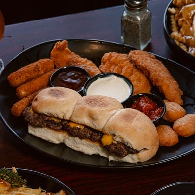 Sliders served with fried sides and dipping sauces.