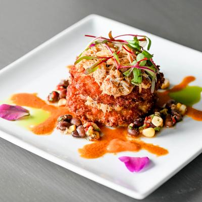 A gourmet dish with shredded meat, colorful sauce splashes, and microgreens.