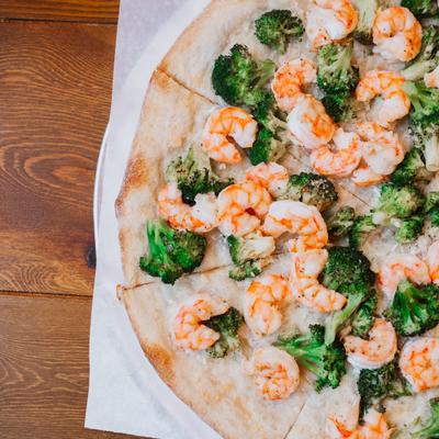 Shrimp and broccoli pizza served on a table