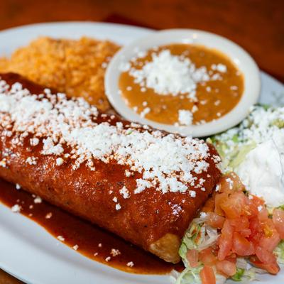Chimichanga, with red sauce and cheese, served with tomato, sour cream, rice, and beans.