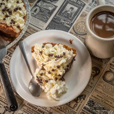 Piece of Chocolate cream pie served alongside a cup of coffee.