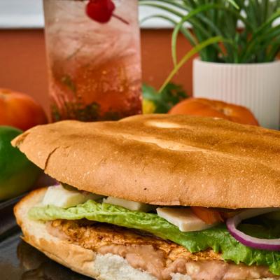 Close-up view of a Mexican torta sandwich with grilled chicken.