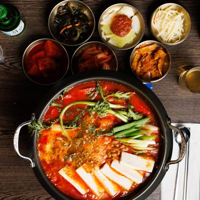 Army Stew with ham, sausage, Spam, baked beans, kimchi, ramen noodles, and sides.