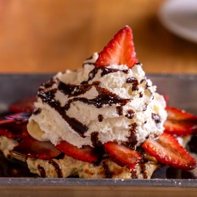 Cookie butter waffle with strawberries, bananas, whipped cream and chocolate sauce.