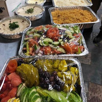 Various foil trays filled with Mediterranean food, including spreads, rice, and salads.