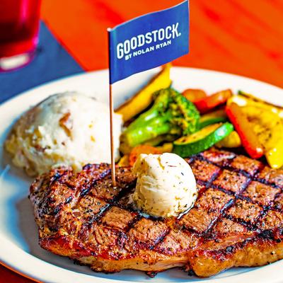 Grilled steak topped with butter, with the  sides of  mashed potatoes and sauteed vegetables.