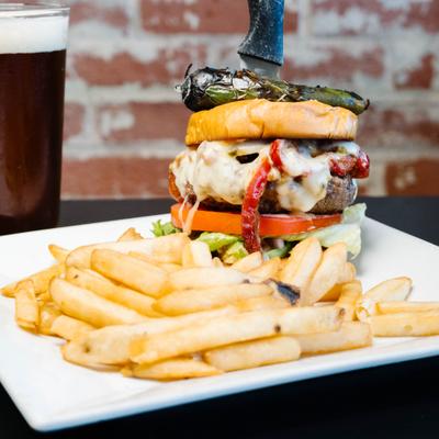 Stacked cheeseburger with a roasted jalapeno and fries.