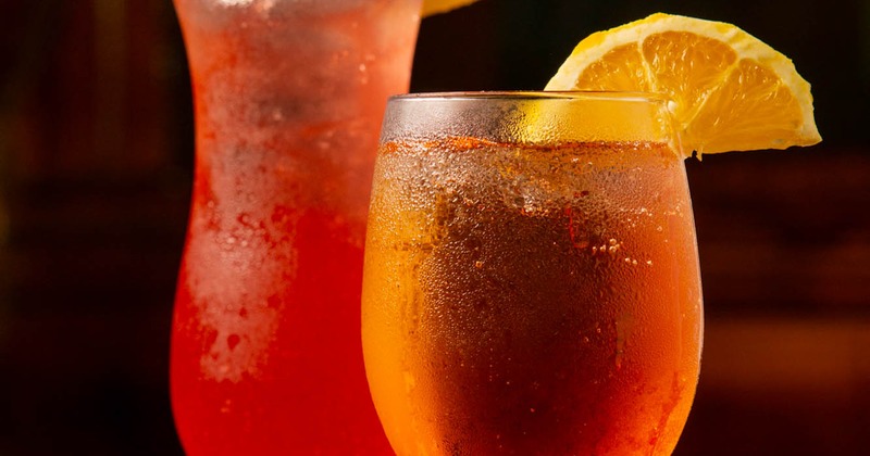 Two refreshing drinks garnished with orange and pineapple slices