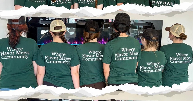 Staff posing in green t-shirts with the phrase "Where Flavor Meets Community"