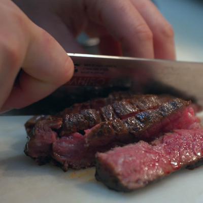Hands slicing meat.