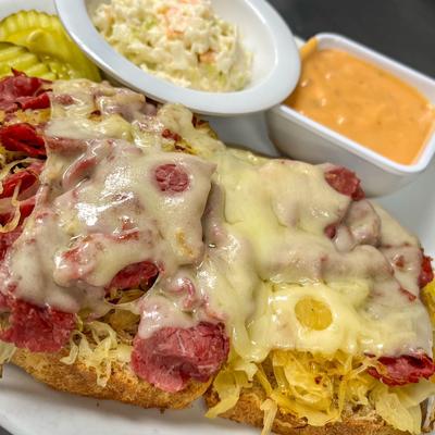 Open-faced Reuben sandwich served with dipp and coleslaw.