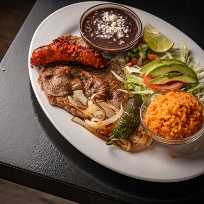 Carne Asada with salad, sausage link, rice, grilled jalapeno, refried beans.