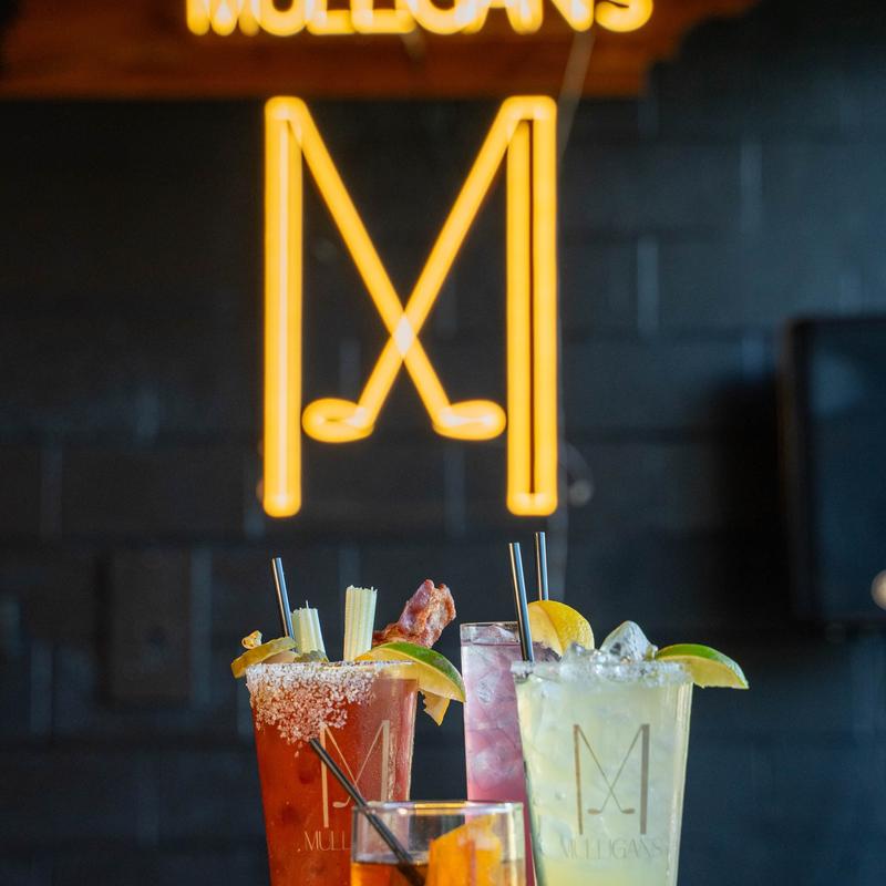 Various cocktails served on the table with a neon sign in the background.