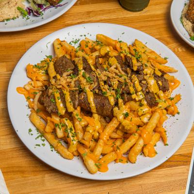 Habibi Fries topped with shawarma meat, cheese sauce and herbs.