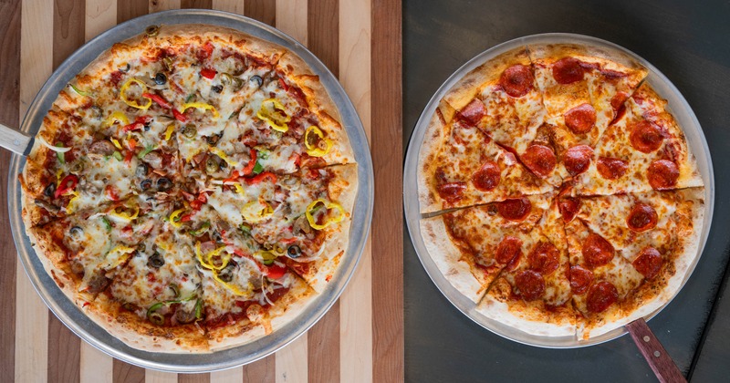 Two pizzas topped with assorted vegetables and pepperoni