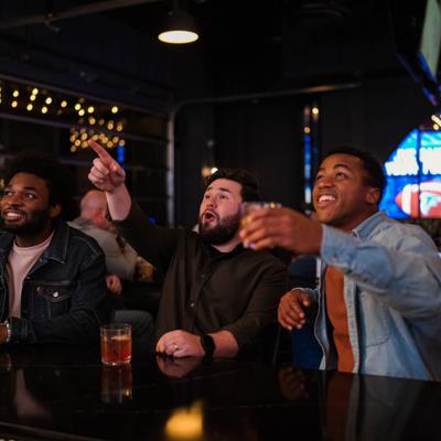 Guys cheering at the bar watching a game.