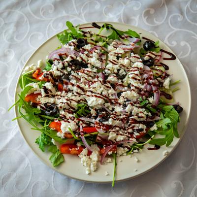 Mediterranean-style salad topped with crumbled feta cheese and a balsamic glaze.