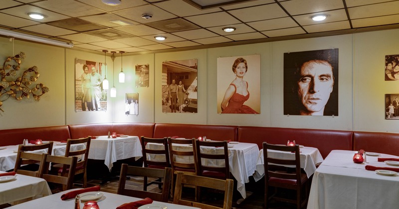 A vintage-style interior - tables, white tablecloths, red napkins, wall photos.