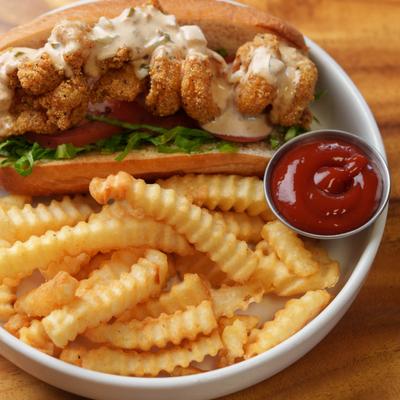 Shrimp Po Boy sandwich served with fries and a dipping sauce.