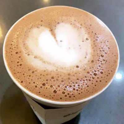 Coffee beverage with a simple latte art, served in a take-away cup.