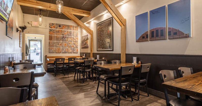 Interior, dining area, wooden top tables for two, four and six people, wall posters and paintings