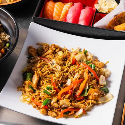 Chicken soba noodles next to assorted nigiri rolls.