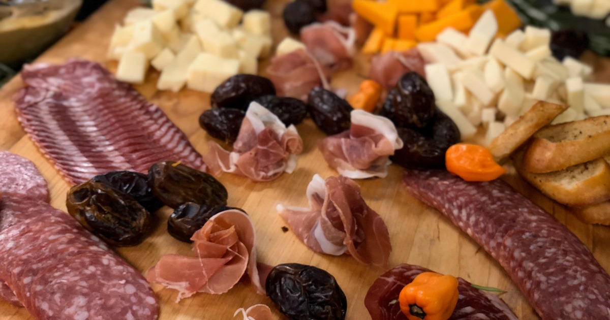 Charcuterie board arranged with various cured meats, cheeses, and accompaniments