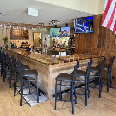 Wood trimmed bar with high stools and televisions.