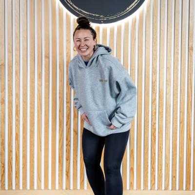 Woman in a light gray ''Hula Pot'' hoodie, front view, zoomed out.