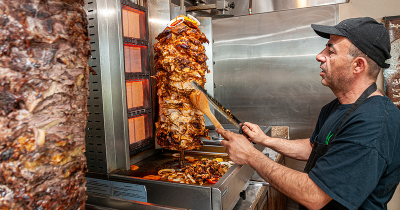 Staff member preparing grilled meat for guests