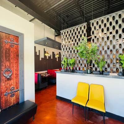 Area with room dividers, potted plants, two chairs, and a leather bench.