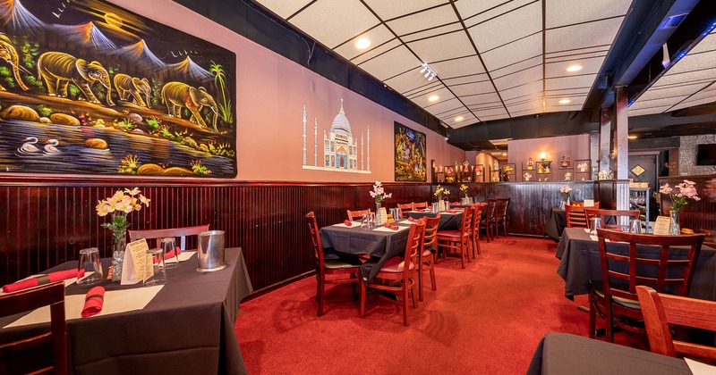 Set tables in a dining area, wall with artworks depicting symbols of India