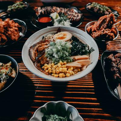 Aji Tonkotsu Ramen bowl surrounded by assorted food dishes.