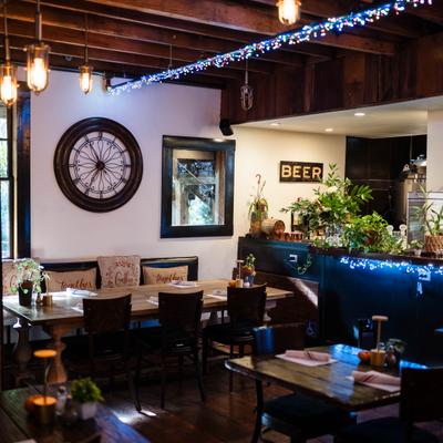 Dining area with a counter, table seating, rustic wooden beams and warm lighting.