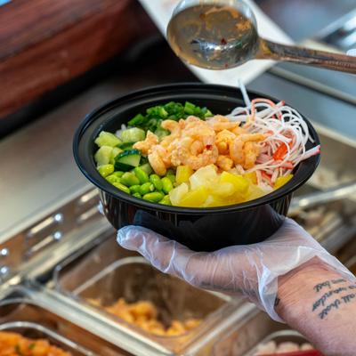 Fresh poke bowl being topped with sauce.